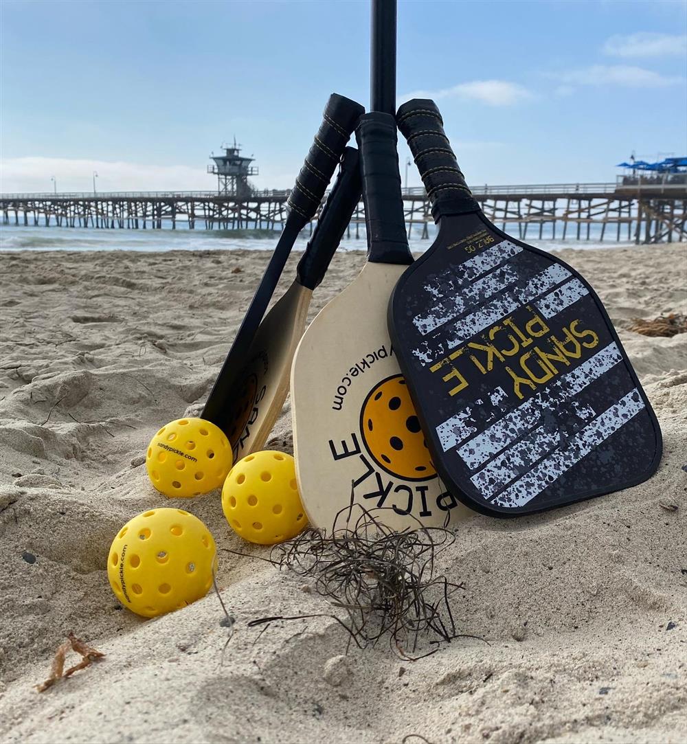 Pickleball paddles and balls resting on the ground beside a court