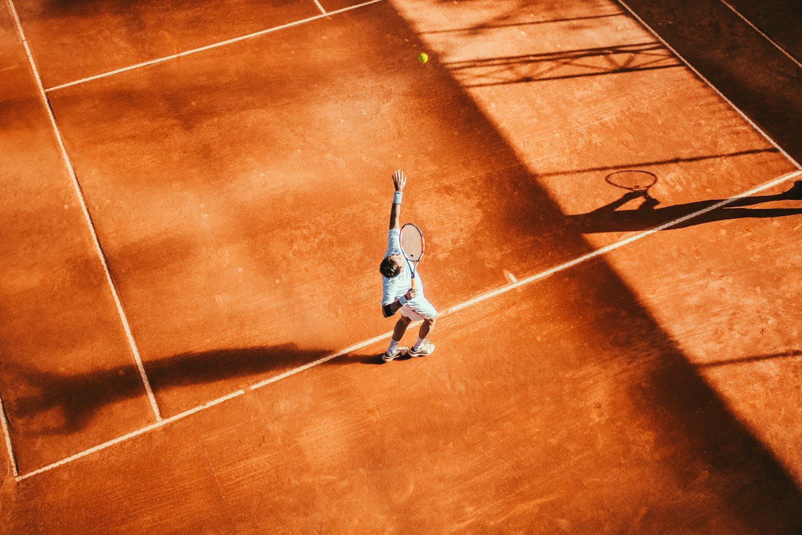 Overhead view of a tennis player serving on a clay court