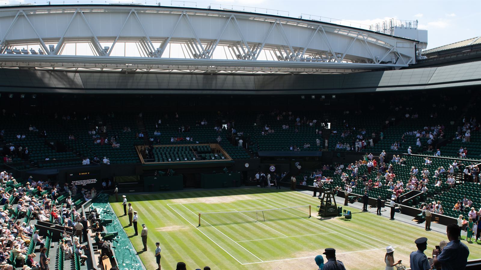Wimbledon Centre Court with the royal box, grass court and crowd under the open roof